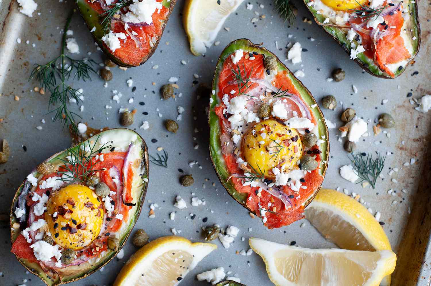 Everything bagel seasoned baked eggs in avocado on a sheet pan.