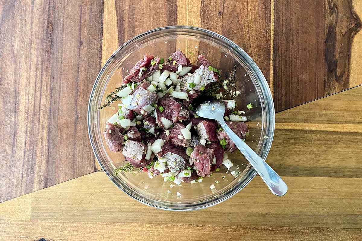 Mixing beef and ingredients in a bowl to make Jamaican Stewed Beef.