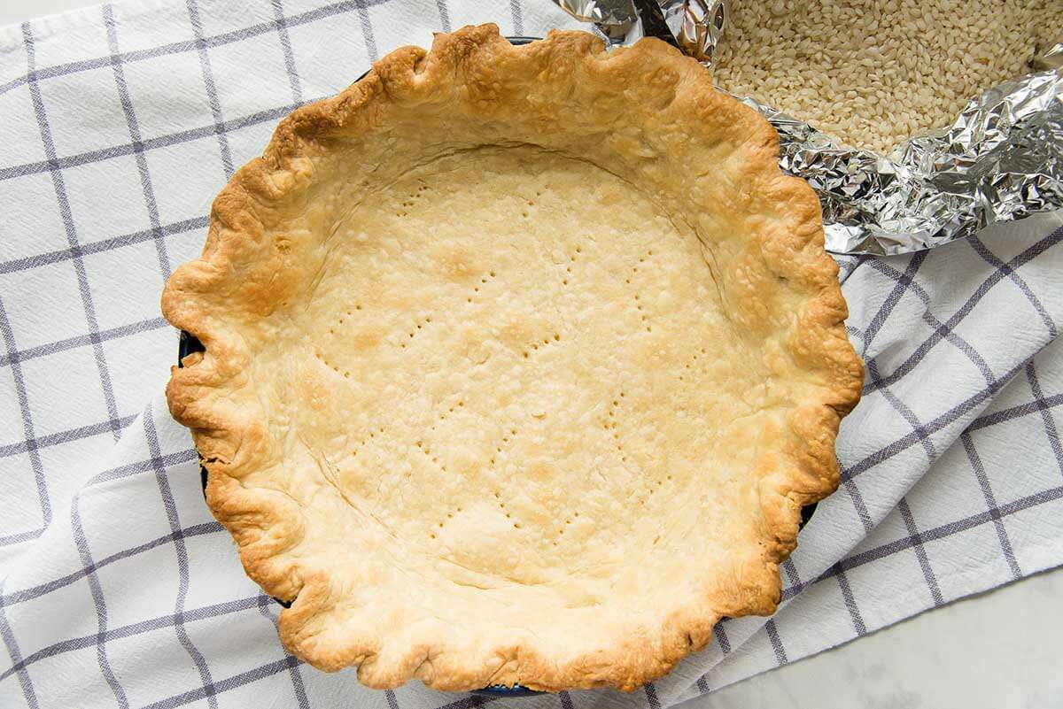 Blind baked pie crust on a checked linen for the best coconut cream pie.