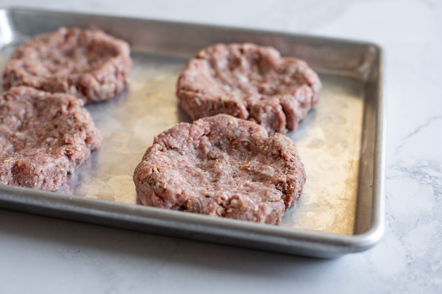 Baking sheet with patties on it to make a ground beef and mushroom recipe.