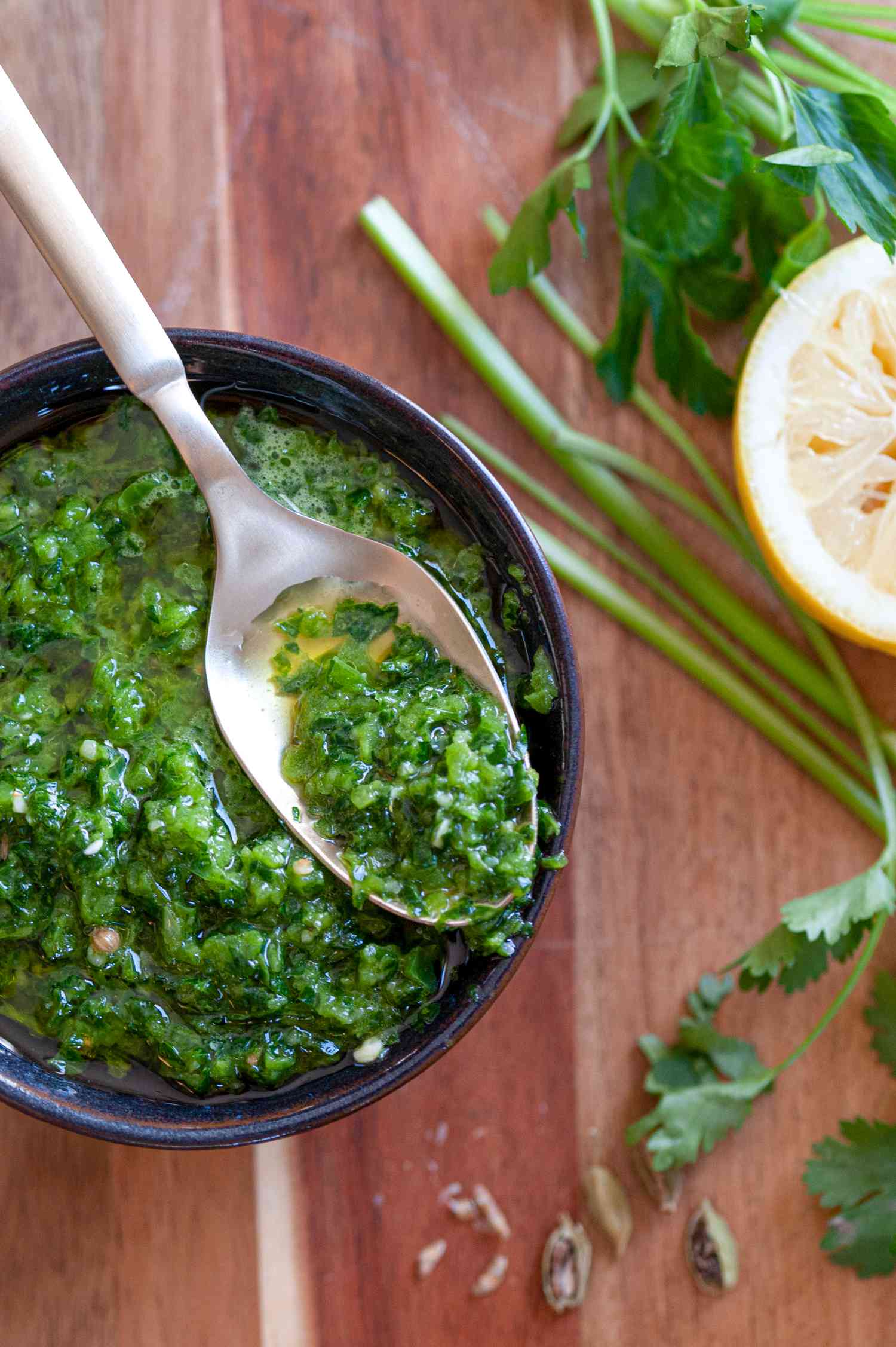Zhoug in a spoon over a black bowl.