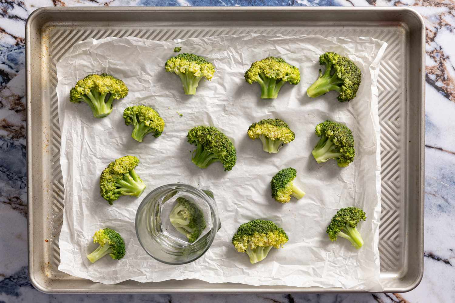 cooked broccoli smashed using the bottom of a glass for crispy parmesan broccoli recipe