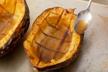Baked acorn squash with sauce spooned overtop.