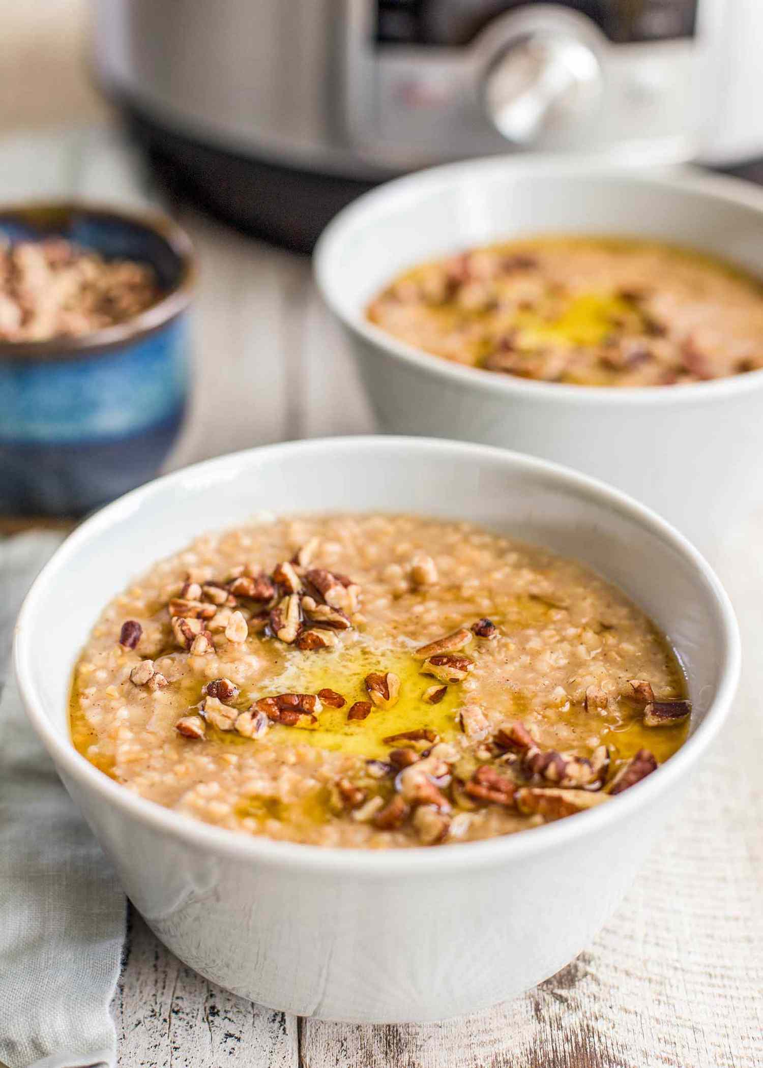 Instant Pot Oatmeal served in bowls and topped with nuts with the instant pot in the background