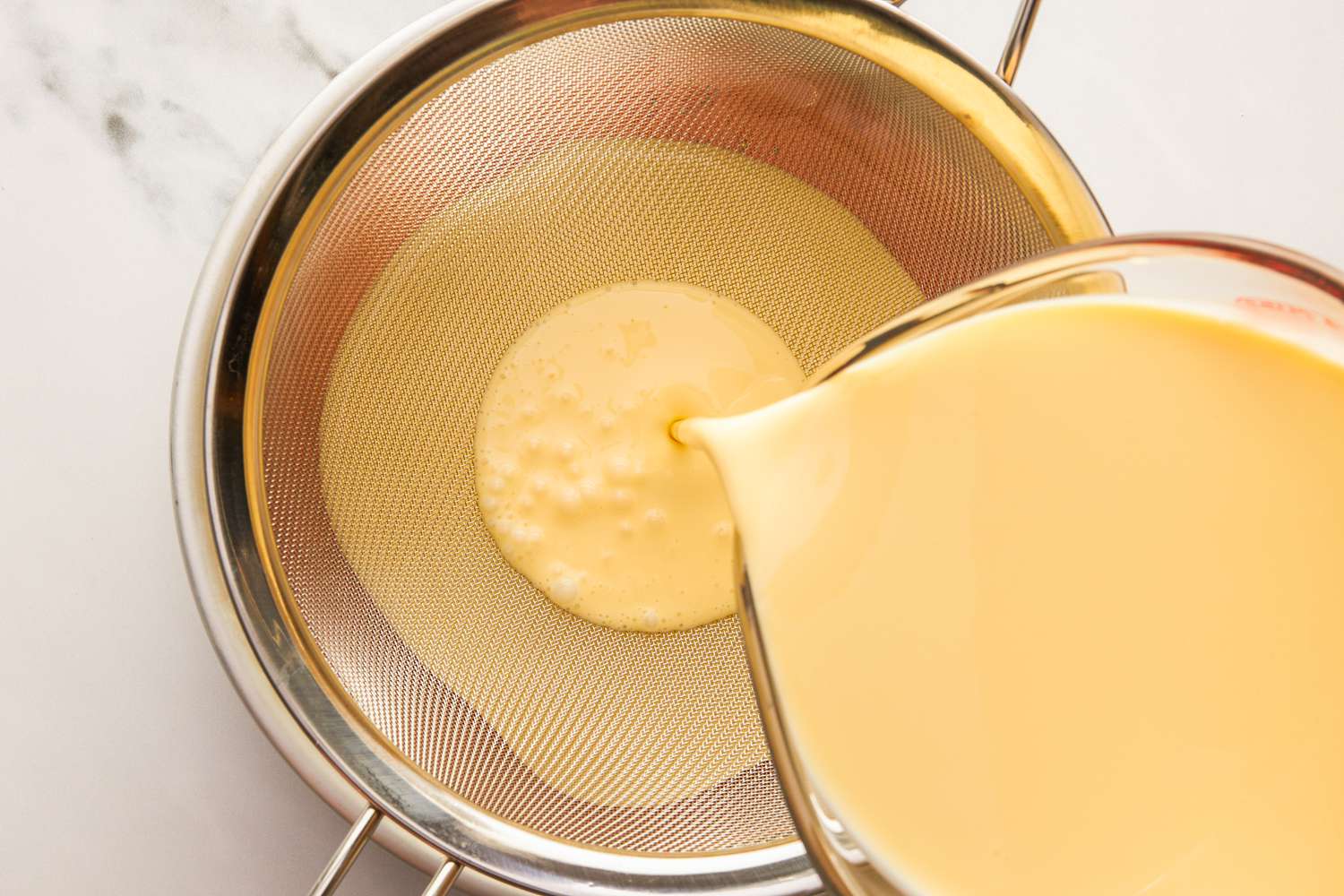 Pouring flan mixture through a sieve