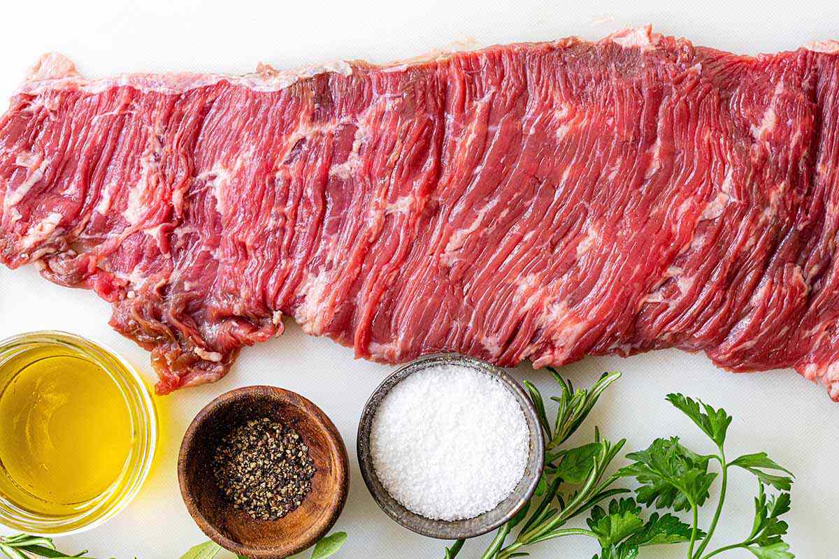 Easy Skirt Steak Recipe - steak on cutting board with salt, pepper, and herbs