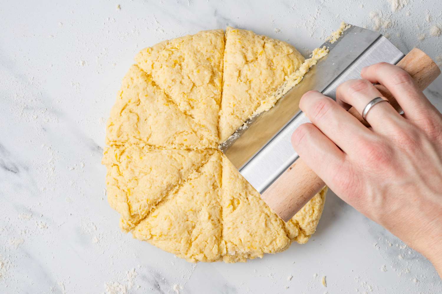 Disk of Lemon Scones Dough Cut into Wedges Using a Bench Scraper
