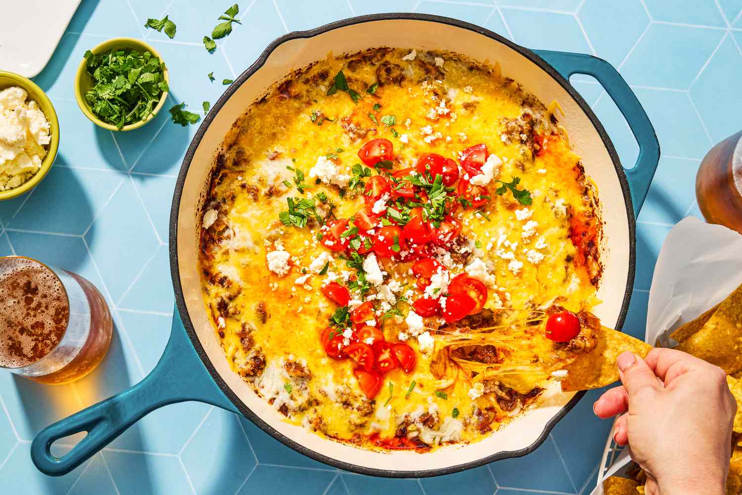 overhead view of Queso Fundido in a skillet, hand pulling dipped chip from it