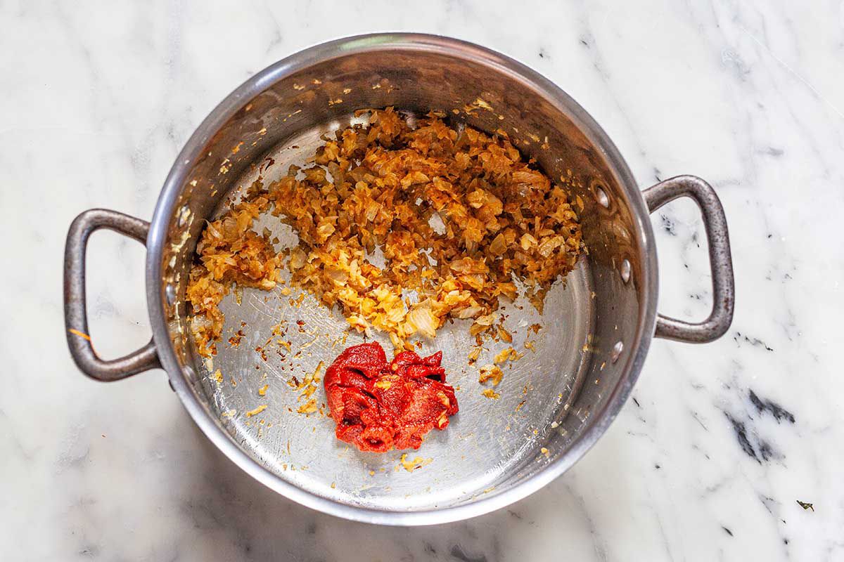 Caramelized onions and tomato paste in the bottom of a soup pot.