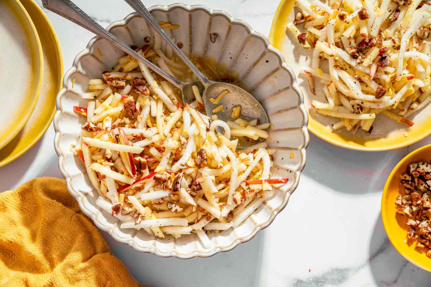 A bowl of kohlrabi and apple salad garnished with nuts served with a spoon