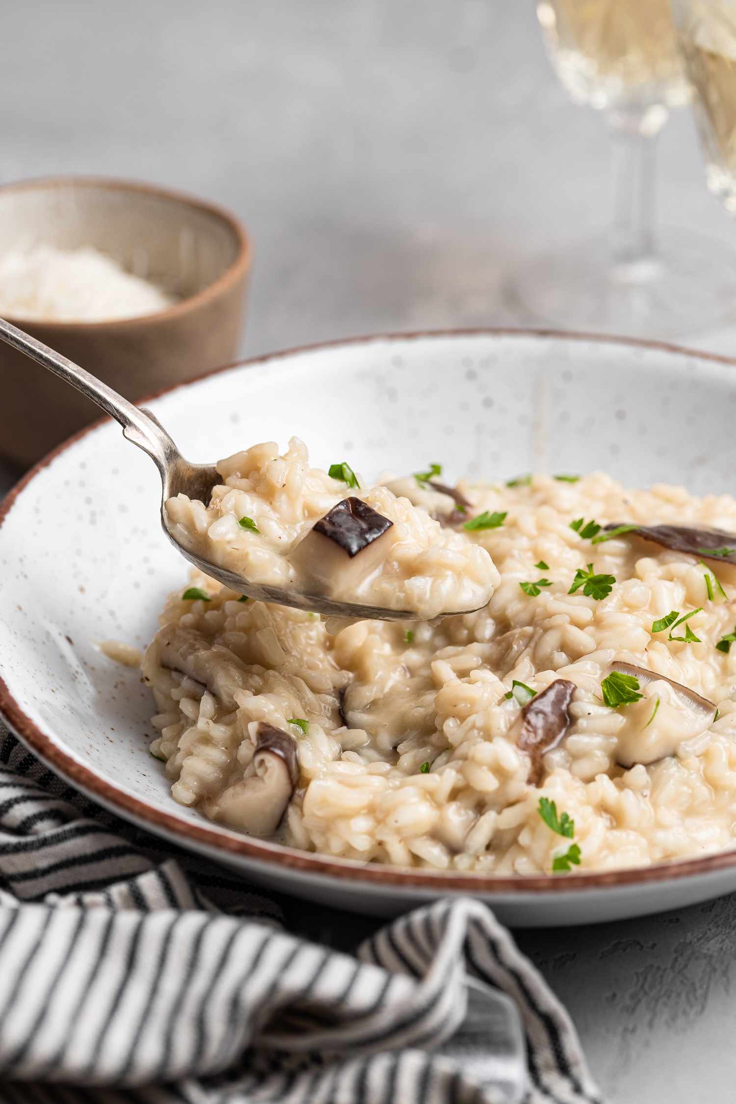 A bowl of mushroom risotto with a spoon scooping risotto out of the bowl.