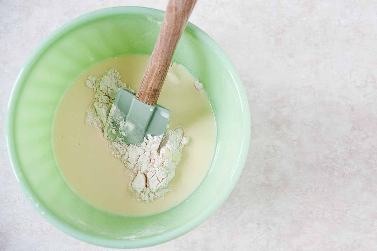Mixing pancake batter in a mixing bowl with a spatula.