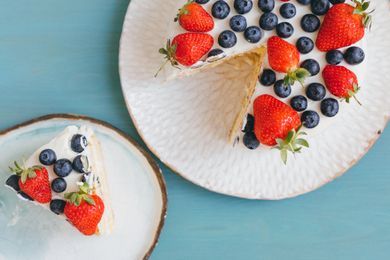 A cake with strawberries and blueberries, slice served separately