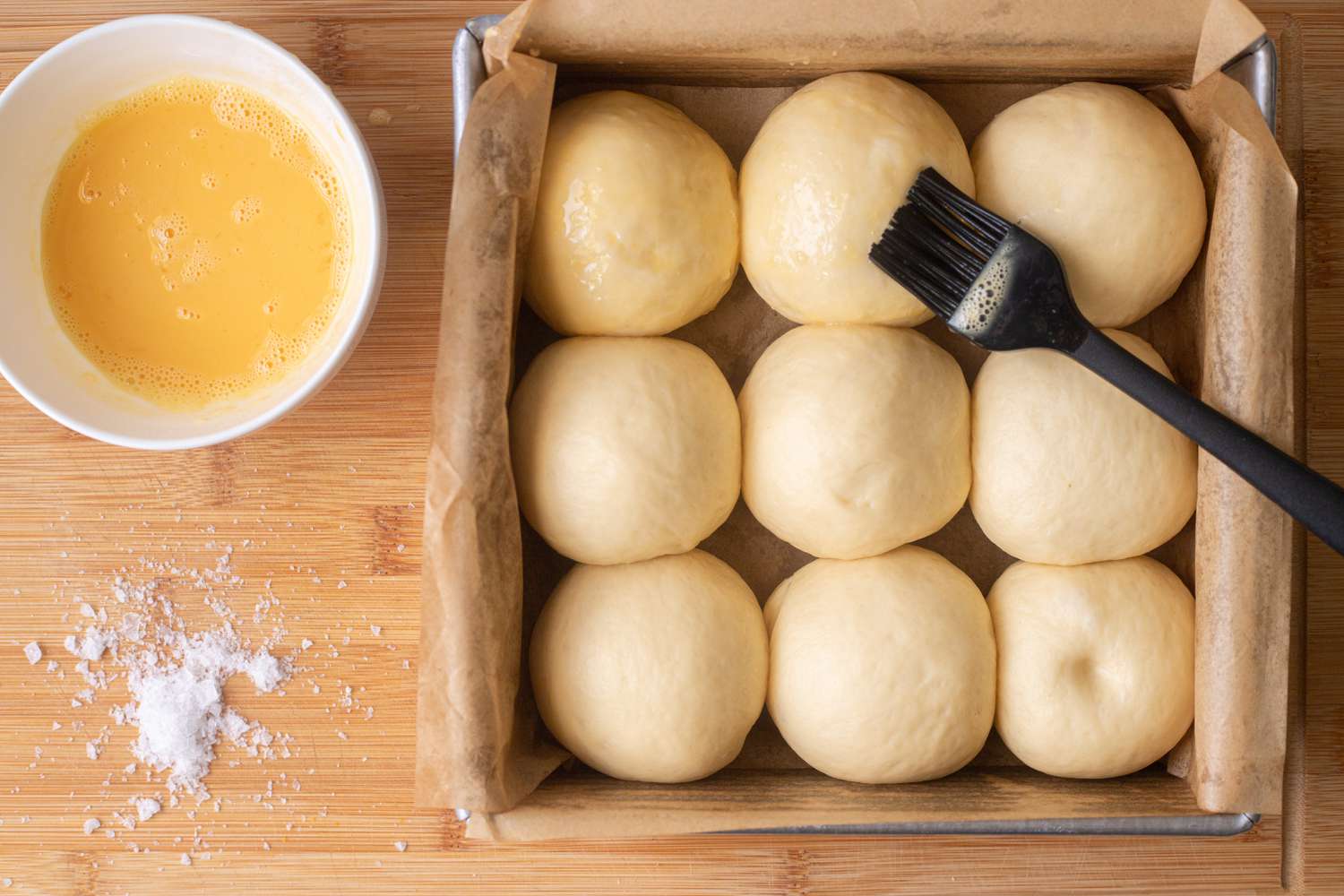 Brushing egg wash on pull apart rolls with garlic and parmesan rolls.