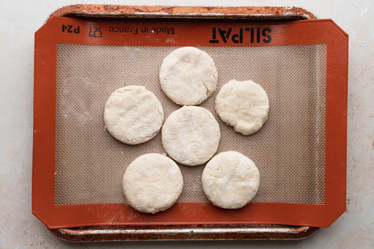Baking sheet with unbaked biscuits set on the baking sheet to make sausage gravy and biscuits.