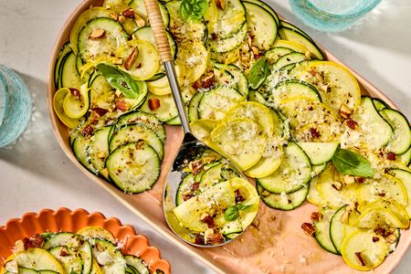 A prepared summer squash salad garnished with herbs and nuts