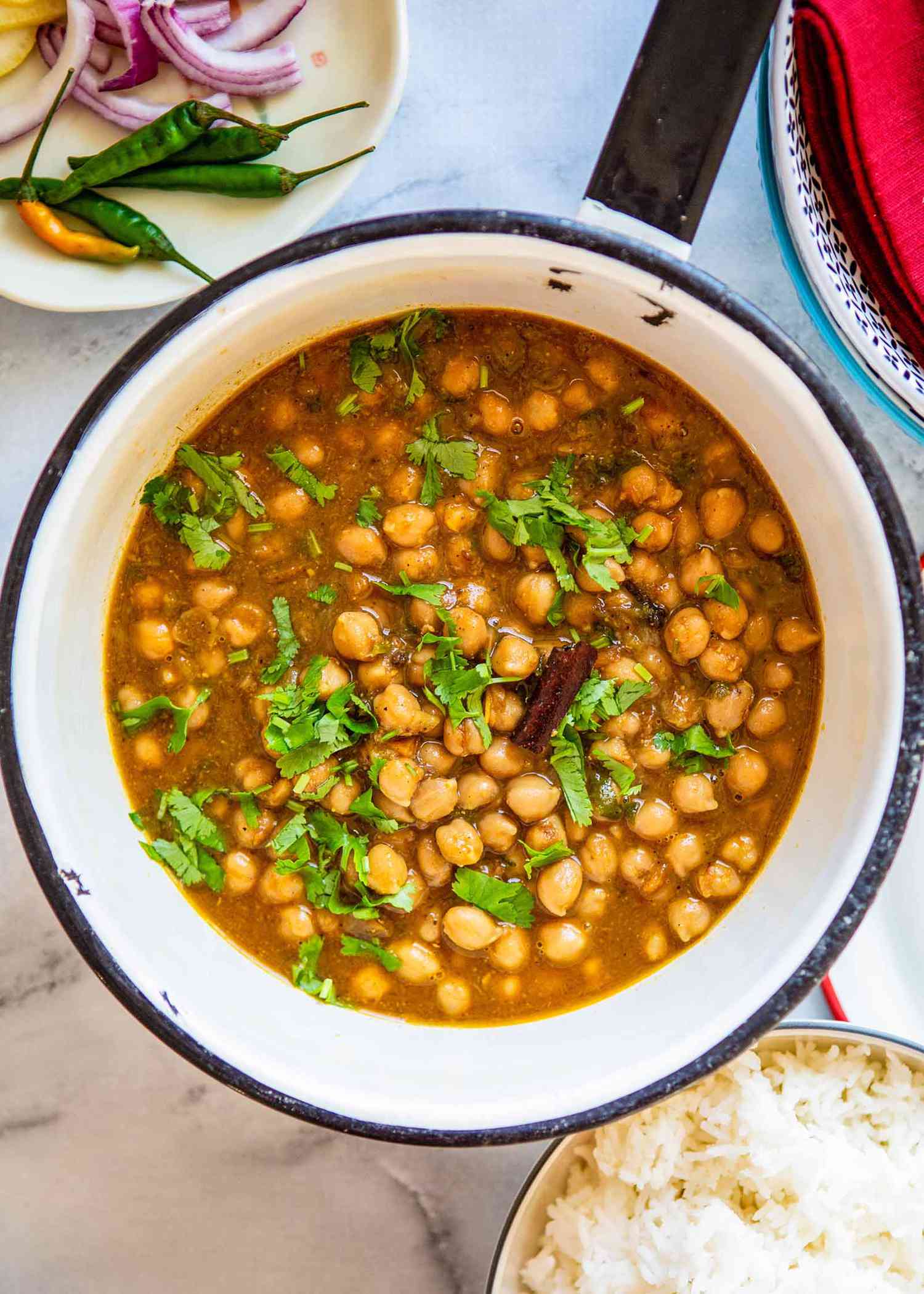 Best Chana Masala - chana masla in pot with fresh green herbs sprinkled on top.
