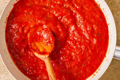 Tomato sauce cooking in a pan with a wooden spoon