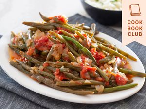 Side view of braised green beans on an oval platter.