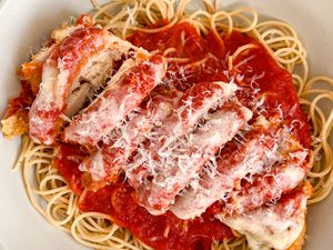 Bowl of chicke parmesan served over pasta with tomato sauce