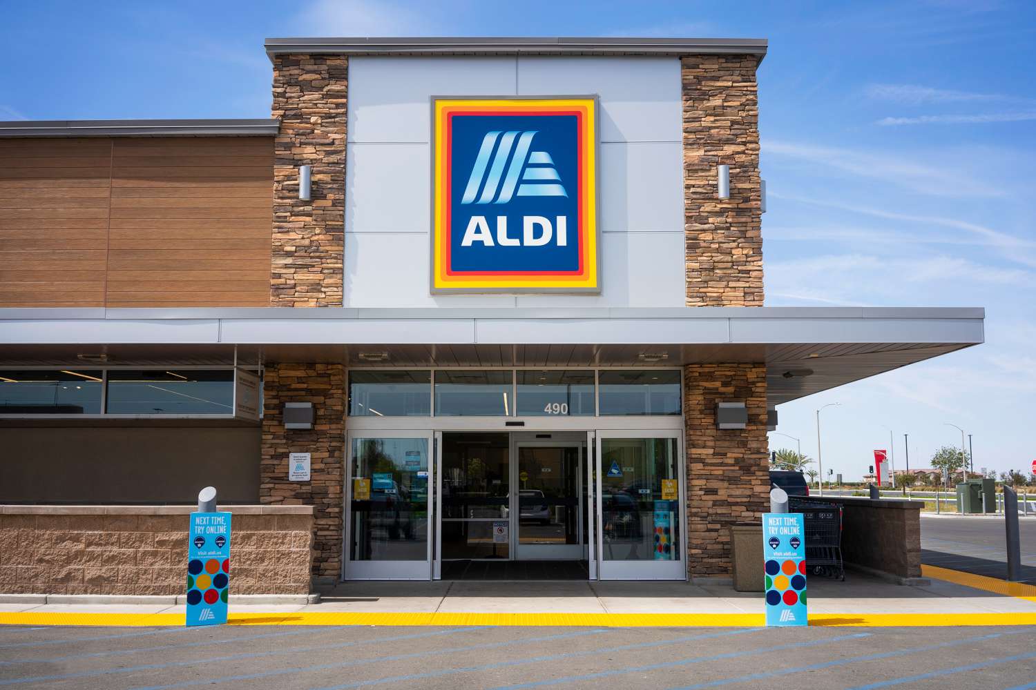 Front entrance and sign of an Aldi grocery store with a mostly clear blue sly above