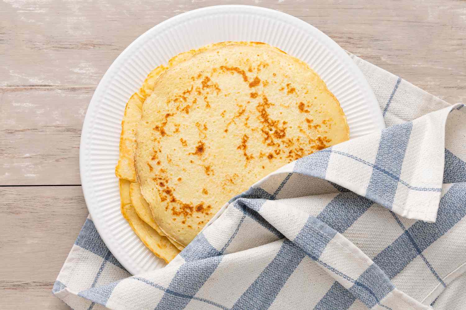 Pannenkoeken (Dutch Pancakes) on a plate covered slightly with a kitchen towel