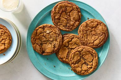 Platter of molasses spice cookies, one plated cookie, and a glass of milk