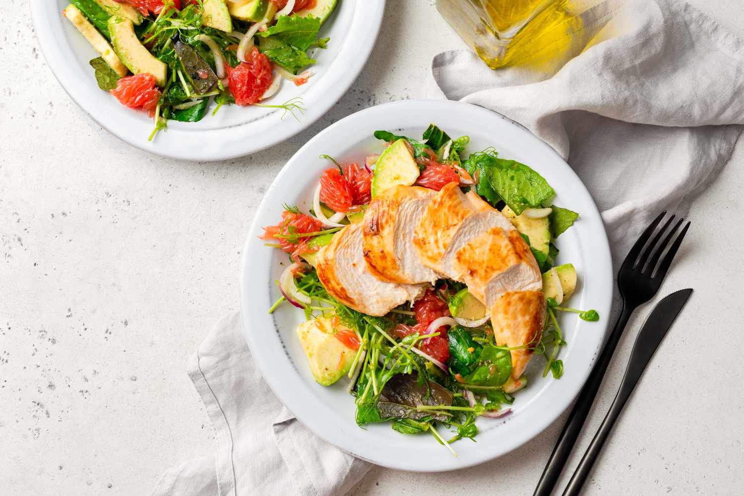 Overhead shot of grilled chicken salad with avocado, lettuce salad and grapefruit served on a plate.
