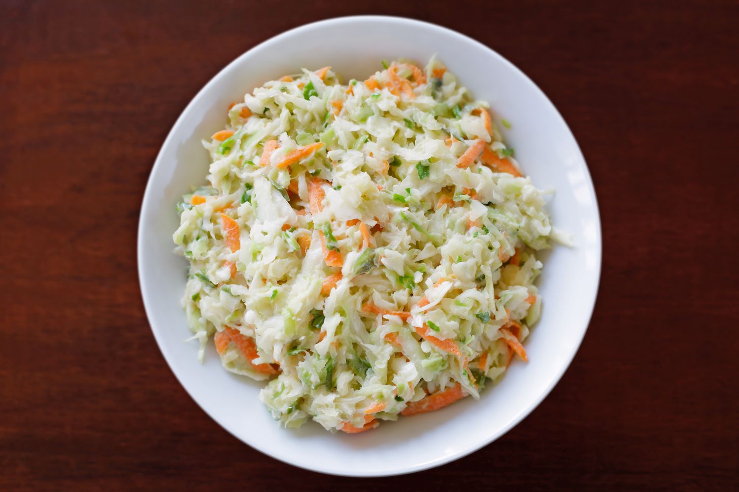 A bowl of coleslaw placed on a wooden surface