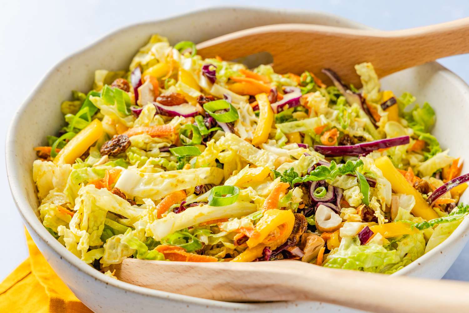 coronation coleslaw with salad serving spoons in a bowl (close-up)