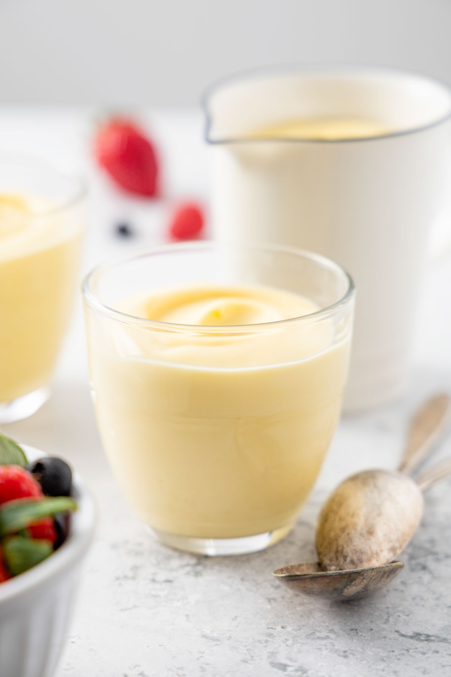 Vanilla Custard in Pudding Jars and Creamer Pitcher Next to Spoons and Berries