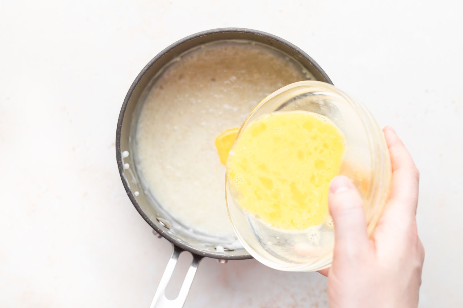 Adding eggs to tapioca pudding being made on the stove.