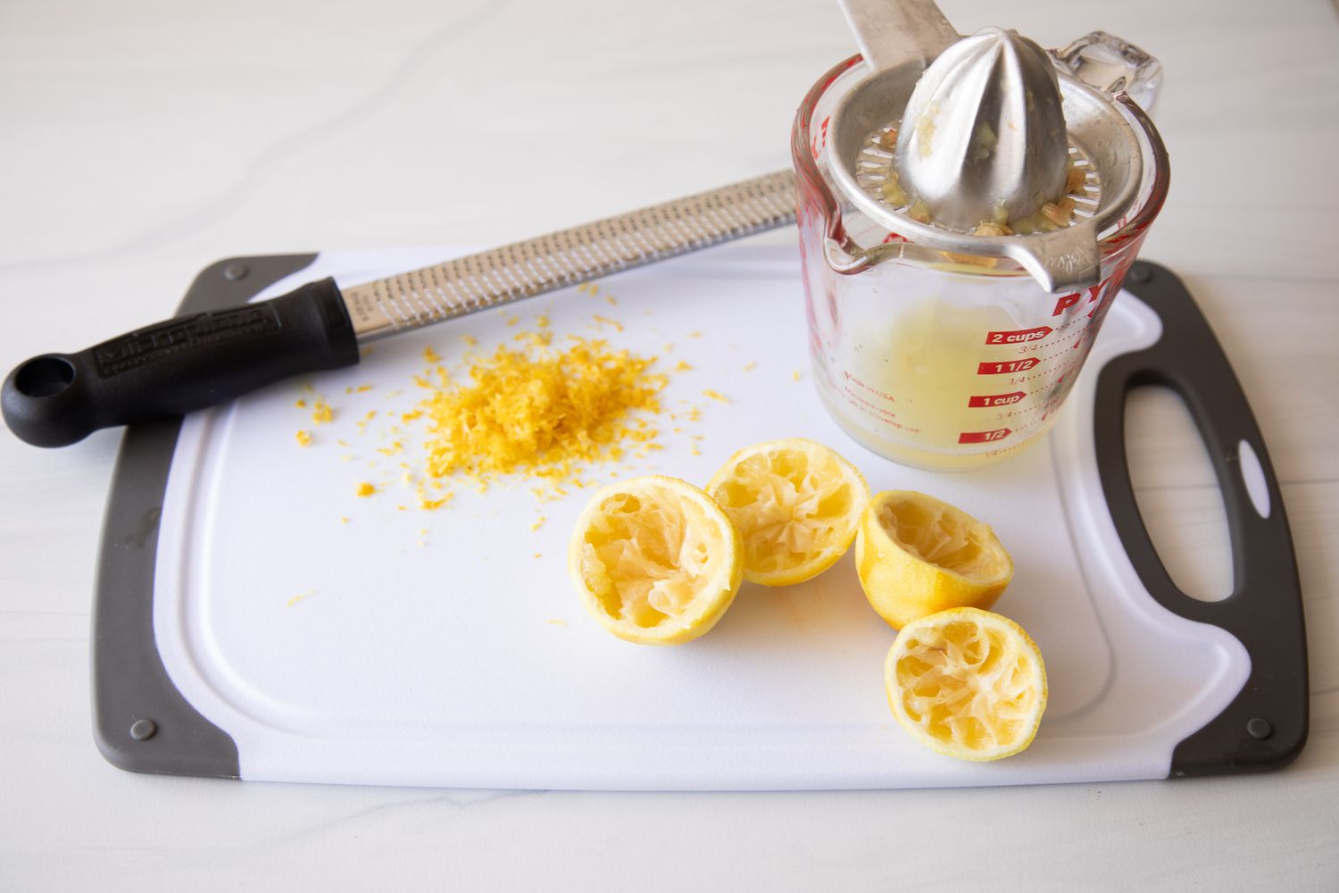 Cutting Board with Halved Lemons, Lemon Zest, and Measuring Cup of Lemon Juice for Green Goddess Pasta Salad
