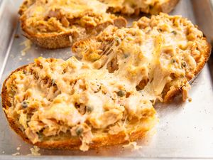 Toasted bread topped with melted cheese and tuna mixture on a baking tray