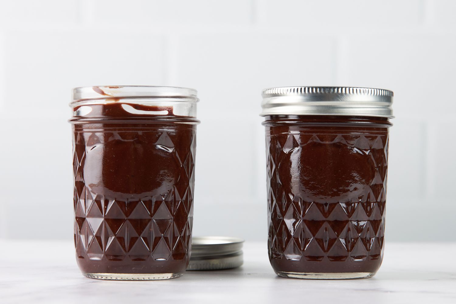 Two pint jars of hot fudge sauce (one jar open, another jar closed) 