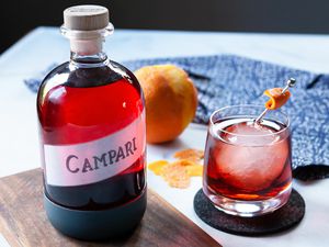 Glass jar filled with Campari substitute. A whiskey glass with a cocktail inside is to the right.