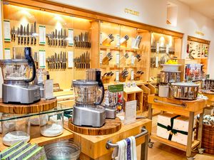 A display of kitchenware and cooking tools in a store featuring a variety of knives food processors and utensils