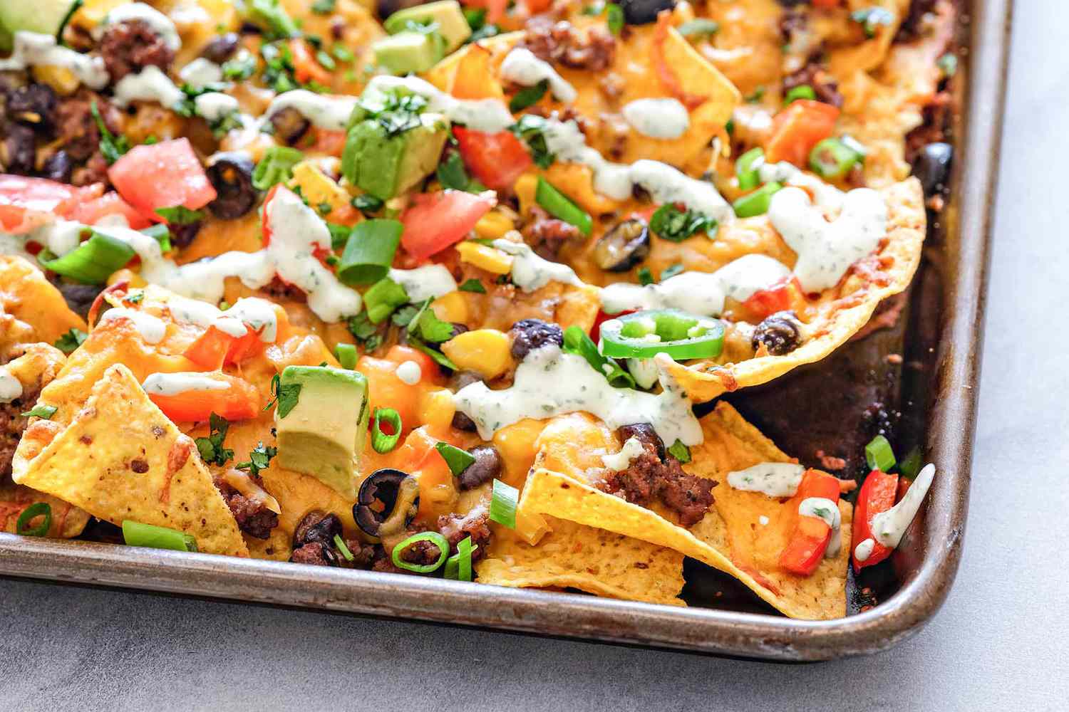 Corner of a sheet pan loaded with homemade nachos