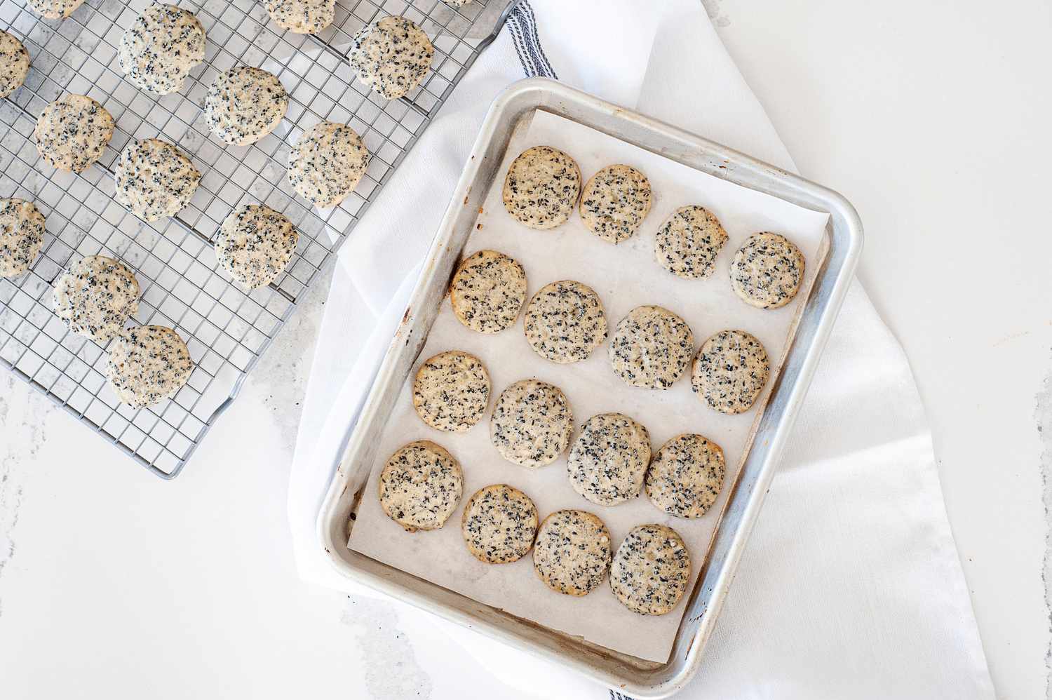 Slice and bake sesame cookies cooking on a rack and on a sheet pan.