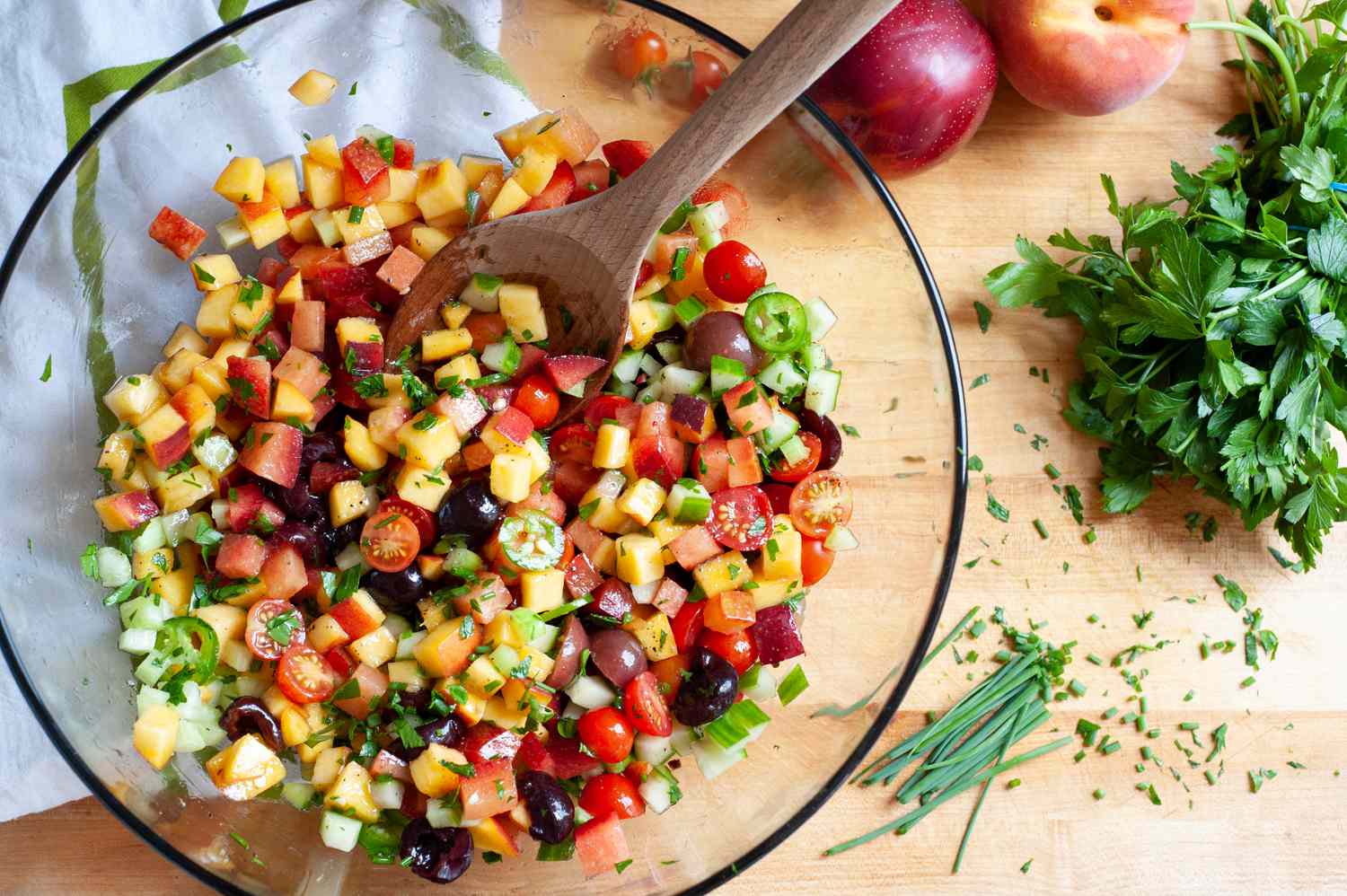 Mixing ingredients in a bowl to make a stone fruit and vegetable salad.