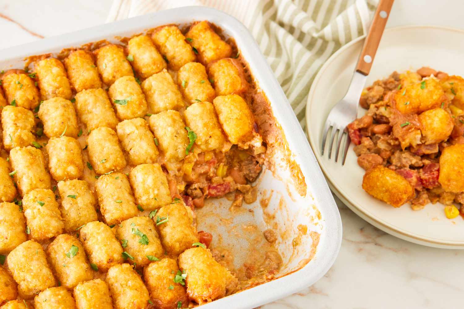 cowboy casserole in a casserole dish next to a plate with a serving
