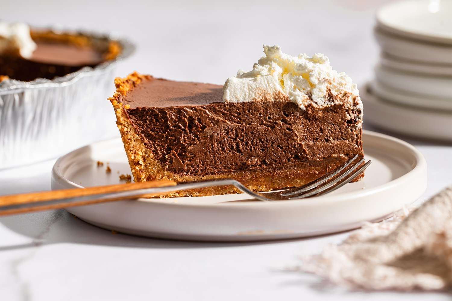 Slice of chocolate cream pie on a white plate with a fork