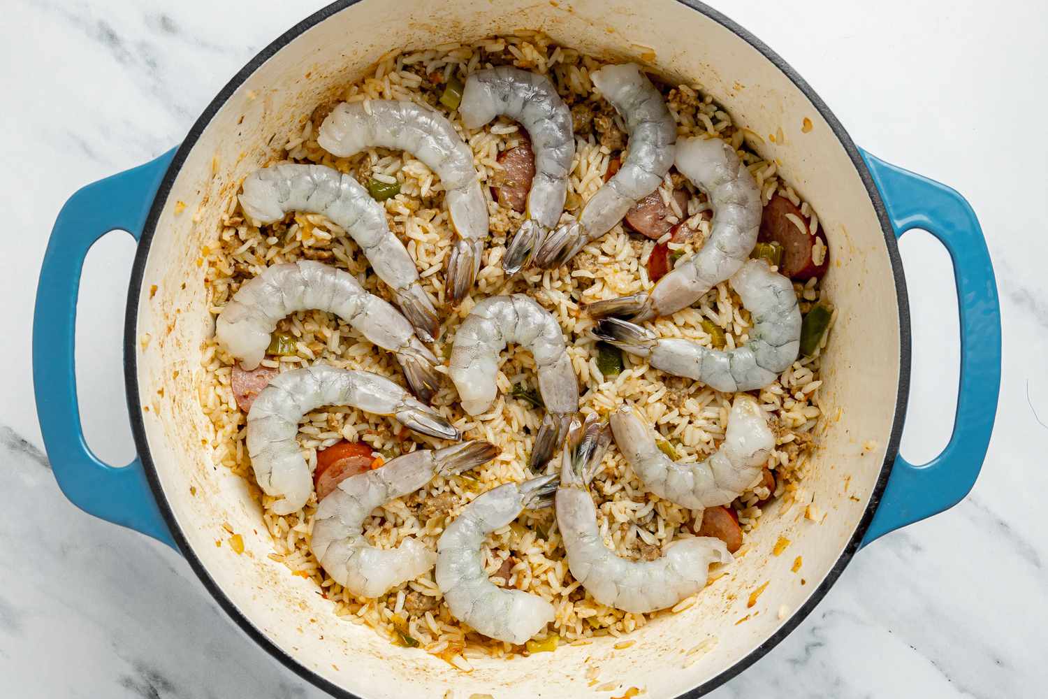 Raw Shrimp (With Tails) Placed on Top of Dirty Rice With Shrimp in the Dutch Oven