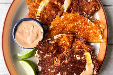 Burnt Cheese Tacos on a Plate with Chipotle Sauce and Lime Wedges