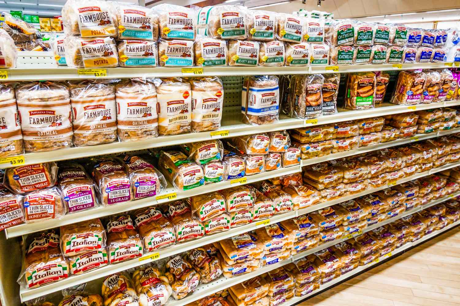 Shelves filled with various brands and types of packaged bread in a grocery store