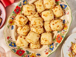 Triscuit appetizers topped with melted cheese on a serving plate with flower design