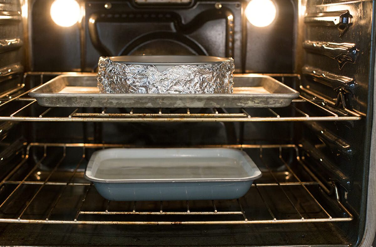 Cheesecake Recipe with Lemon - pan of water in oven with cheesecake on sheetpan on upper rack