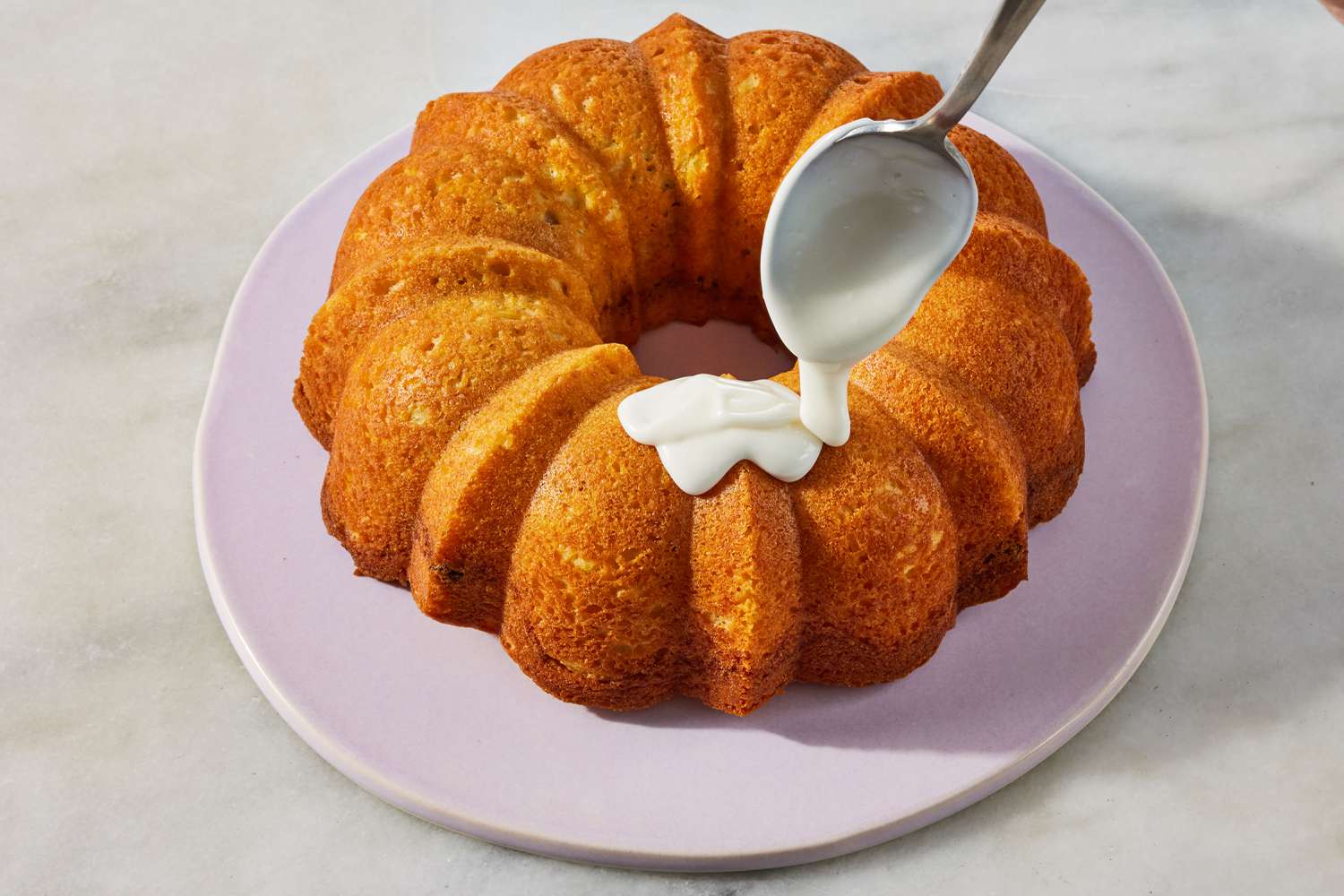 large spoon drizzling icing mixture on top of Sock It to Me Cake on a platter