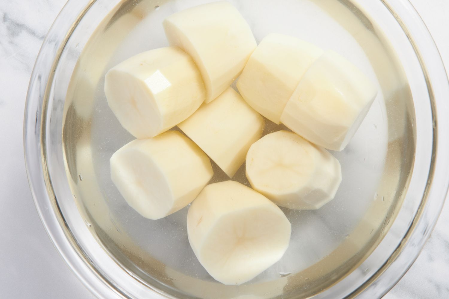 Russet potatoes in a bowl of water for fondant potatoes recipe