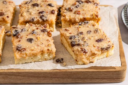 Slices of Lane cake with a fruit and nut topping on a wooden board
